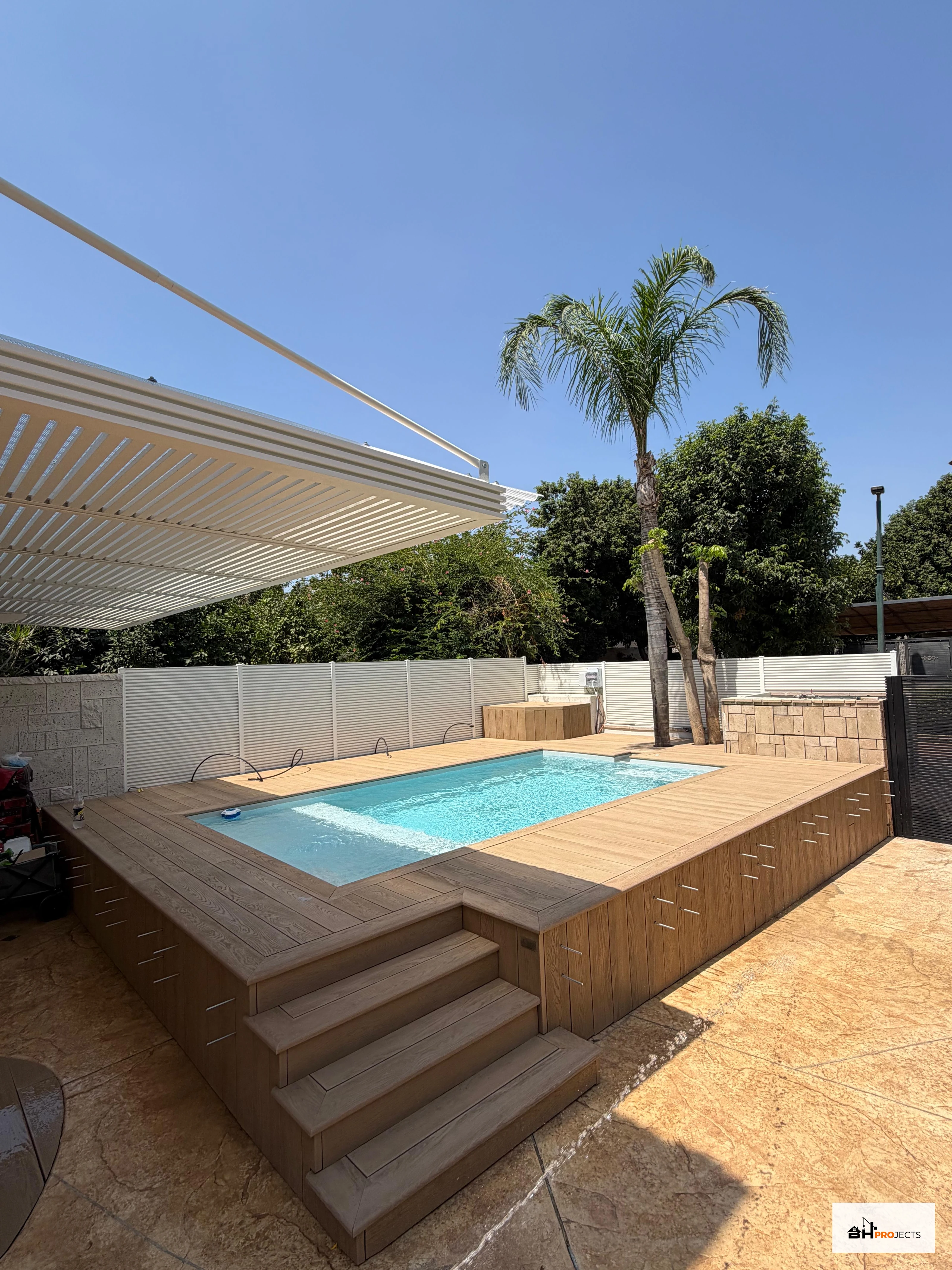 דק מילבורד בגוון אלון מוזהב סביב בריכת פיברגלס, עם מדרגות וחיפוי דפנות