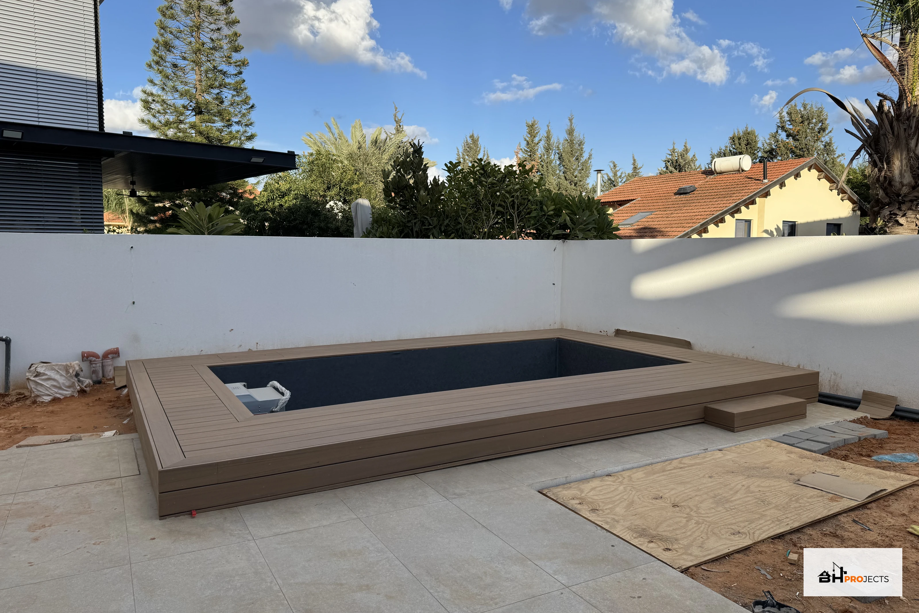 דק TimberTech בגוון Coconut מקיף בריכת זרמים ריקה, בזמן השלמת סביבת החוץ